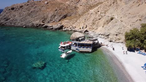 Turistas-Bajando-De-Un-Barco-En-La-Playa-Con-Aguas-Turquesas-En-El-Mar-Mediterráneo,-Al-Sur-De-Creta,-Grecia