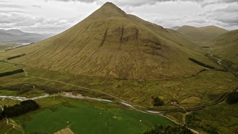 Lush-Green-Grass-Covered-Mountain-With-River-Running-Around-It,-Skye-Scotland