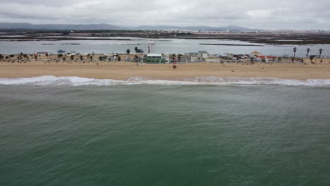Drohnenaufnahme-Von-Praia-De-Faro---Drohne-Entfernt-Sich-Vom-Strand,-Im-Hintergrund-Der-Flughafen