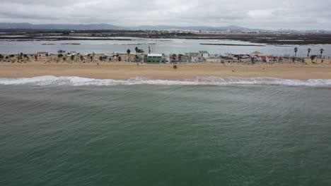 Drone-shot-of-Praia-de-Faro---drone-is-moving-away-from-the-beach-with-the-airport-in-the-background