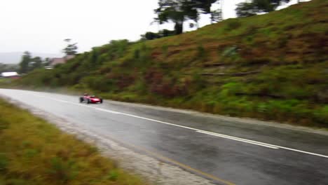 Red-Classic-race-car-speeds-up-course-in-the-rain-at-Simola-Hillclimb