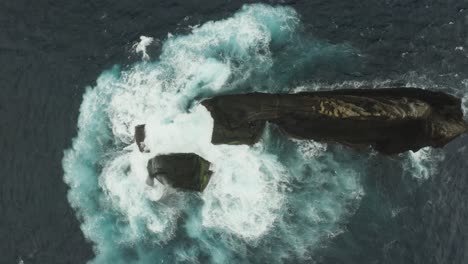 Aerial-view-of-the-ocean-swelling-against-a-rocky-outcrop
