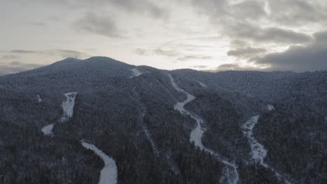 Snow-frosted-peak-of-an-abandoned-ski-mountain-at-sunset-AERIAL