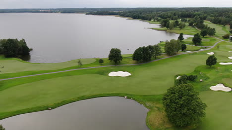 Aerial-birds-eye-view-of-golf-course-by-a-lake