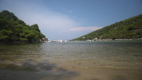 Low-angle-view-of-clear-warm-water-washing-onto-sandy-beach-in-lagoon-of-beautiful-island-in-Croatia