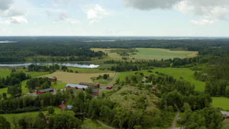 Aerial-view-around-houses-and-buildings-at-a-farm,-on-the-countryside,-partly-sunny,-summer-day,-in-Fagervik,-Inkoo,-Finland---orbit,-drone-shot