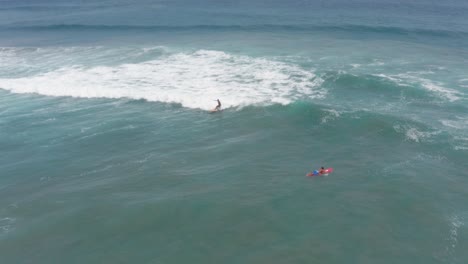 Surfing-on-Pacific-Ocean-Waves,-Surfers-Near-Coast-of-Acapulco,-Mexico,-Aerial-Pull-Back-View