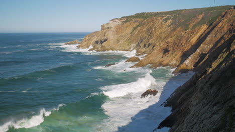 Tilt-up-shot-of-waves-crashing-into-cliffs-of-Mossel-Bay,-South-Africa