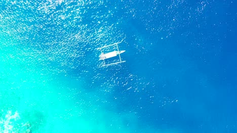 Boot-Schwimmt-über-Einer-Ruhigen,-Klaren-Meeresoberfläche-In-Blauen,-Azurblauen-Farben-Und-Reflektiert-Die-Sonnenstrahlen-Eines-Heißen-Sommertages-Auf-Indonesischen-Inseln