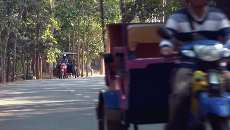Medium-Exterior-Shot-of-Traffic-Road-Through-Forest-Angkor-Wat-Daytime