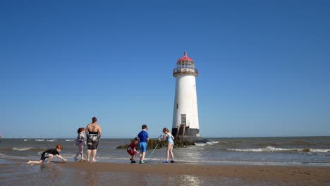 Tourist-family-children-splashing-and-playing-at-Landmark-Ayr-lighthouse-sandy-beach