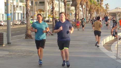 People-jogging-running-on-a-street-near-a-beach-in-Tel-Aviv,-Izrael