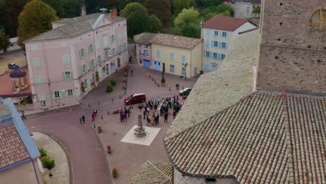 Provence,-Frankreich---Frisch-Vermähltes-Paar-Und-Ihre-Gäste-Fotografieren-Nach-Der-Hochzeitszeremonie-Glücklich-Vor-Der-Kirche-Mit-Tauben,-Die-Auf-Dem-Kirchturm-Sitzen---Drohnenaufnahme-Aus-Der-Luft