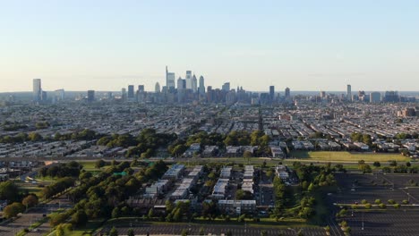 Aerial-trucking-shot-of-Philadelphia-skyline-urbanscape-in-distance-on-horizon-with-neighborhoods