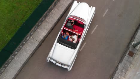 Aerial-shot-of-a-bride-and-her-mother-being-driven-in-a-vintage-convertible-car