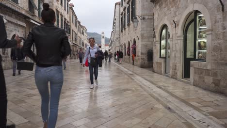 Dolly-in-of-a-young-couple-of-tourists-walking-on-Stradun,-the-main-street-of-Dubrovnik