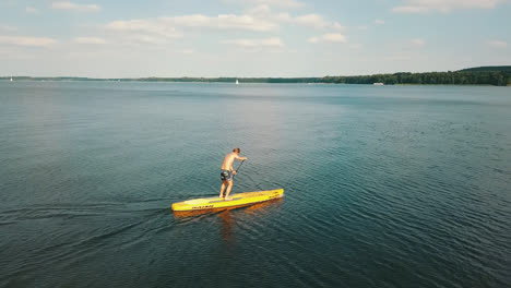 Guy-on-a-yellow-Nash-Standup-Paddle-Bord-surfing-on-the-Mueggelsee-in-Berlin-followed-by-a-drone