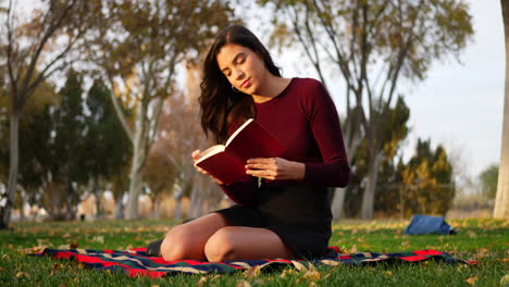 A-gorgeous-young-woman-student-reading-a-book-or-novel-outdoors-on-a-school-campus-before-class-SLIDE-RIGHT