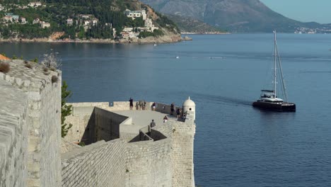 Der-Südliche-Abschnitt-Der-Mauer-In-Der-Altstadt-Von-Dubrovnik-Mit-Sehr-Wenigen-Touristen-Aufgrund-Von-Covid-Und-Einem-Vorbeitreibenden-Segelboot