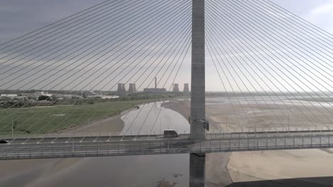 Vehicles-crossing-contemporary-Mersey-Gateway-bridge-aerial-view-at-low-tide-dolly-right-slow