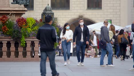 A-couple-walks-with-face-masks-to-protect-themselves-from-the-coronavirus-in-downtown-munich