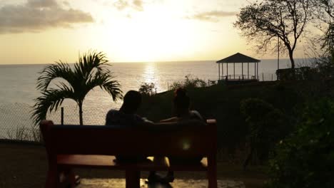 Couple-in-love-sitting-on-a-park-bench-overlooking-the-ocean-in-Tobago