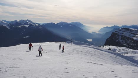 Zeitlupenaufnahme,-Skifahrer-Fahren-Den-Berg-Hinunter,-Malerische-Aussicht-Auf-Die-Mit-Schnee-Und-Nebel-Bedeckte-Bergkette