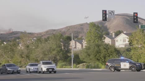 A-Cal-Fire-C-130-Hercules-tanker-plane-makes-a-retardant-drop-on-the-California-Wild-Fires-while-police-help-evacuate-on-the-streets