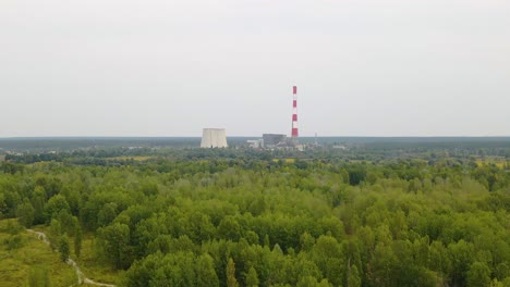 Aerial-view-towards-the-TES-6-Coal-fired-power-factory,-over-green-forest,-dark,-overcast-day,-in-Kiev,-Ukraine---dolly,-drone-shot
