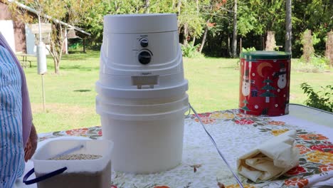 Woman's-hands-feeding-the-hopper-for-a-personal-sized-electric-wheat-mill