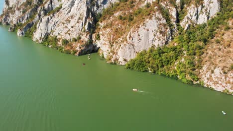 Stunning-drone-aerial-view-of-Danube-river-canyon,-surrounding-mountains-and-boats