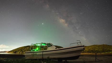 Pequeño-Bote-Vacío-Iluminado-Bajo-La-Isla-De-Lantau-Vía-Láctea-Cielo-Nocturno-Luces-De-Tiro-Timelapse