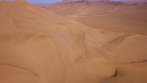 Aerial-shot-in-the-Atacama-desert-showing-a-large-golden-sand-dune-and-sand-being-blow-in-the-wind