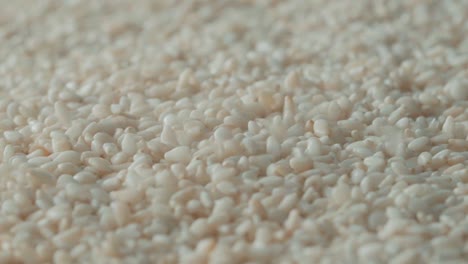 white-sesame-seeds-pouring-on-full-frame-sesame-pile-background,-Extreme-close-up-shot