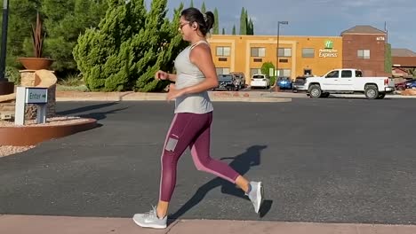 Female-runner-jogging-along-pathway-in-Los-Angeles,-side-follow-slow-motion