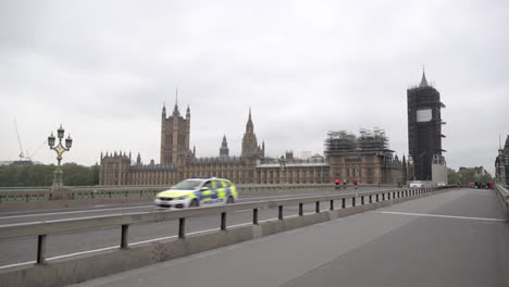Ein-Polizeiauto-Fährt-Während-Des-Coronavirus-Ausbruchs-An-Den-Parlamentsgebäuden-Vorbei,-Während-Es-Eine-Fast-Verlassene-Westminster-Brücke-überquert
