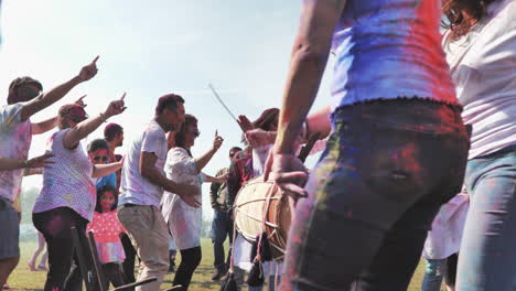 Gente-Colorida-En-El-Festival-Holi-Bailando-Alrededor-Del-Baterista,-ángulo-Bajo,-Cámara-Lenta