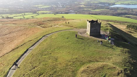 Oben-Läufer-Auf-Dem-Gipfel-Des-Rivington-Tower,-Lancashire-Reservoir,-Landschaft,-Luftaufnahme,-Wegziehen,-Umlaufbahn-Nach-Links