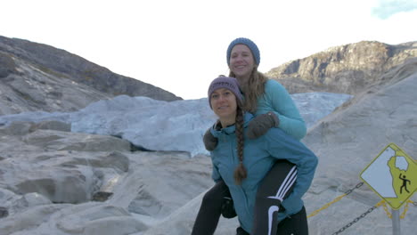 Dos-Chicas-Posan-Para-Una-Foto-Divertida-Junto-A-Un-Glaciar-En-Noruega