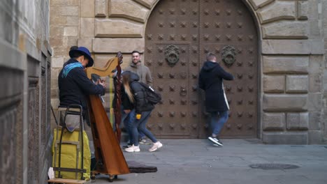 Los-Turistas-Se-Detienen-Para-Escuchar-El-Arpa-De-Madera-Clásica-De-La-Calle-En-La-Calle-Medieval-De-Barcelona