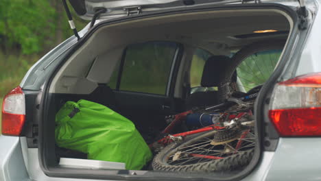 Young-man-packs-a-Subaru-Crosstrek-with-mountain-bike-and-hiking-backpack-for-a-camping-trip-in-the-summer-in-Pennsylvania