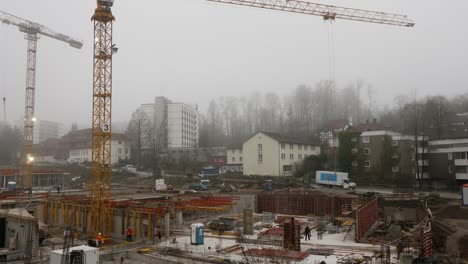 Several-construction-workers-are-working-on-the-new-children's-clinic-on-a-foggy-day-and-in-the-background-a-long-truck-falls