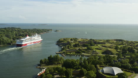 Drone-shot-following-the-Viking-line,-a-large-passenger-ferry,-passing-the-Suomenlinna-and-Vallisaari-islands,-sunny,-summer-day,-in-Helsinki-archipelago,-Finland---Dolly,-aerial-view