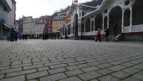 People-Walking-on-Paved-Road-in-Karlovy-Vary,-Czech-Republic-on-Cloudy-Day,-Low-Angle-Slow-Motion
