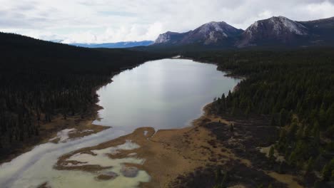 Johnson-Range-lake-with-mountains-and-forest,-aerial-drone-shot