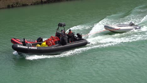Border-force-officer-pull-in-abandoned-migrant-boats-into-Dover-port,-Kent,-UK