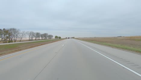 POV-driving-on-a-divided-highway-past-harvested-fields-on-a-cloudy-winter-day-in-rural-eastern-lowa