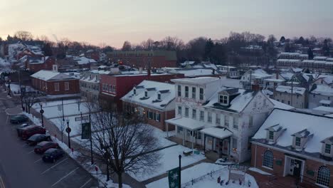 Aerial-of-small-town-in-winter-snow,-decorated-for-Christmas-holidays