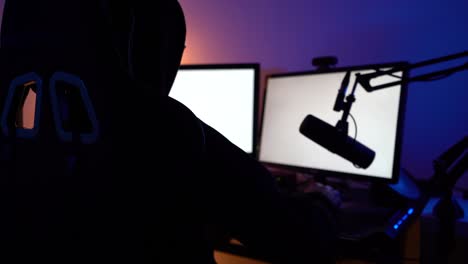 Dark-hooded-guy-on-blank-monitor-screen-with-microphone-close