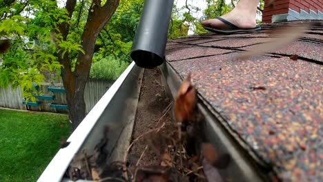 A-leaf-blower-is-seen-blowing-leaves-and-debris-out-of-a-rain-gutter-on-a-roof-in-slow-motion